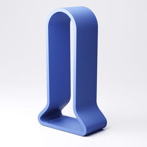 Peut inclure: Un objet bleu en forme de U, moderne, avec un ext&eacute;rieur textur&eacute; et nervur&eacute;. Le design pr&eacute;sente un sommet arrondi et une base plate. L'objet est de couleur unie et semble &ecirc;tre fait d'un seul mat&eacute;riau.
