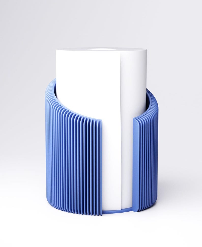 May include: A modern blue toilet paper holder with a vertical slatted design. The holder is a cylinder shape and partially surrounds a white roll of toilet paper. The design is minimalist and contemporary.