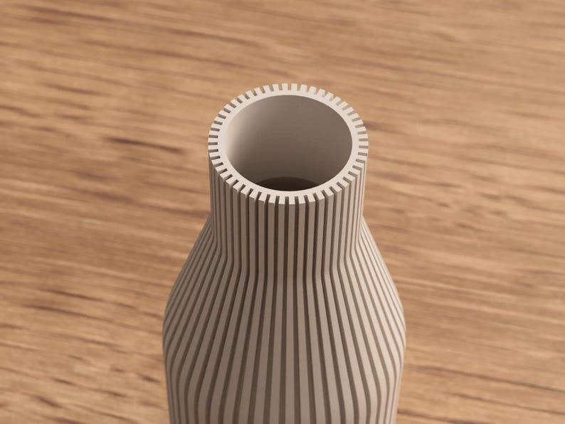 May include: A cream-colored vase with vertical, evenly spaced grooves. The vase has a wide opening and a rounded body, set against a wooden surface. The design is modern and minimalist, suitable for home decor.