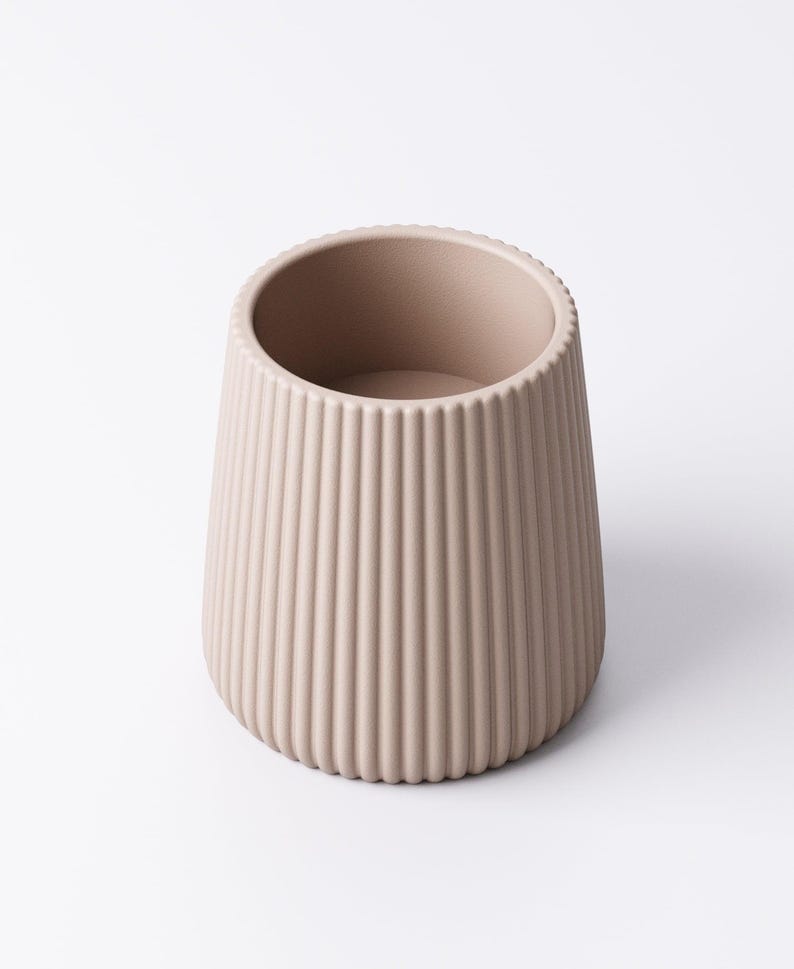 May include: A beige, ribbed ceramic vase with a rounded base and a wide opening. The vase has vertical grooves running from the base to the rim. The neutral color and simple design make it suitable for various decor styles.