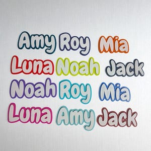 May include: Colorful name cutouts in various colors, including teal, orange, red, yellow, purple, and pink. Names include Amy, Roy, Mia, Luna, Noah, and Jack. Each name has a white outline, creating a 3D effect. The names are arranged on a white background.