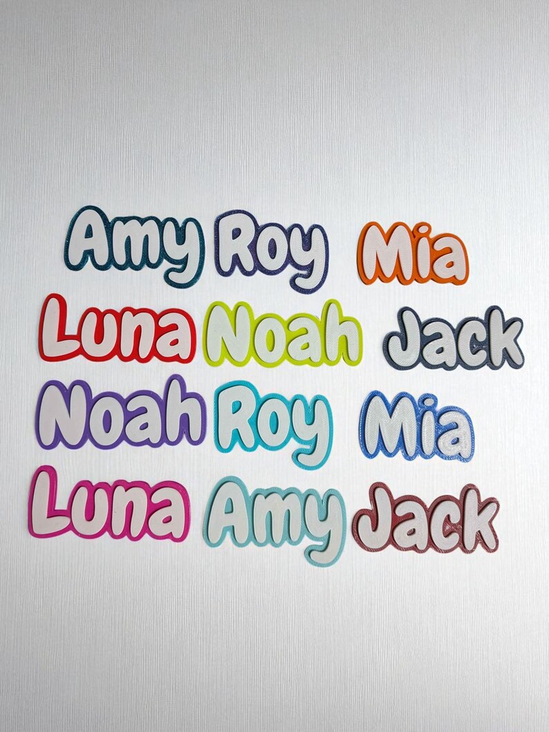 May include: Colorful name cutouts in various colors, including teal, orange, red, yellow, purple, and pink. Names include Amy, Roy, Mia, Luna, Noah, and Jack. Each name has a white outline, creating a 3D effect. The names are arranged on a white background.