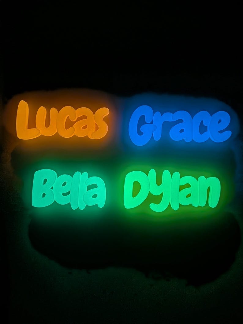 May include: Four illuminated name signs: Lucas in orange, Grace in blue, Bella in green, and Dylan in green. The names are in a playful font, set against a dark background.