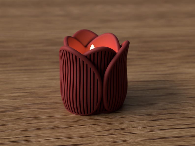 May include: A burgundy tulip-shaped candle holder with vertical lines, holding a lit white candle. The candle holder is made of a solid material and sits on a wooden surface. The interior of the tulip is a warm orange color.