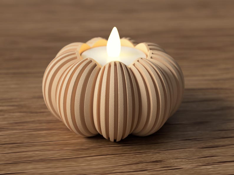 May include: A decorative candle holder shaped like a pumpkin, made of light-colored wood. The candle holder has vertical grooves and holds a small, glowing LED candle with a flickering flame. The candle holder sits on a wooden surface.