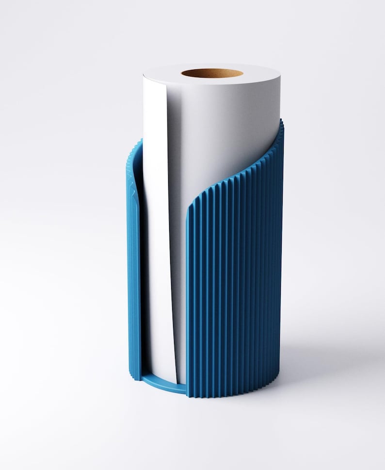 May include: A white paper roll is held within a blue, vertically ribbed holder. The holder has a curved design, with a rounded base and open sides to display the paper. The paper roll has a brown cardboard core.