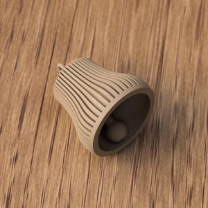 May include: A beige bell-shaped object with a small clapper inside. The bell has a series of vertical, curved lines that create a striped pattern. The bell is resting on a wooden surface.