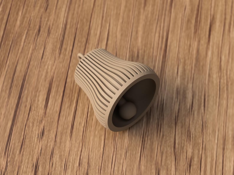 May include: A beige bell-shaped object with a small clapper inside. The bell has a series of vertical, curved lines that create a striped pattern. The bell is resting on a wooden surface.