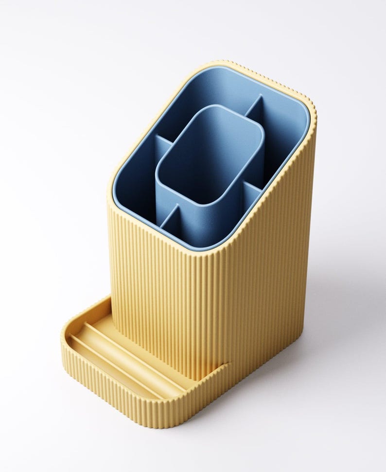 May include: A yellow and blue desk organizer with a ribbed exterior. The organizer has multiple compartments and a small tray. The interior is blue, and the exterior is yellow. The organizer is designed to hold pens, pencils, and other office supplies.