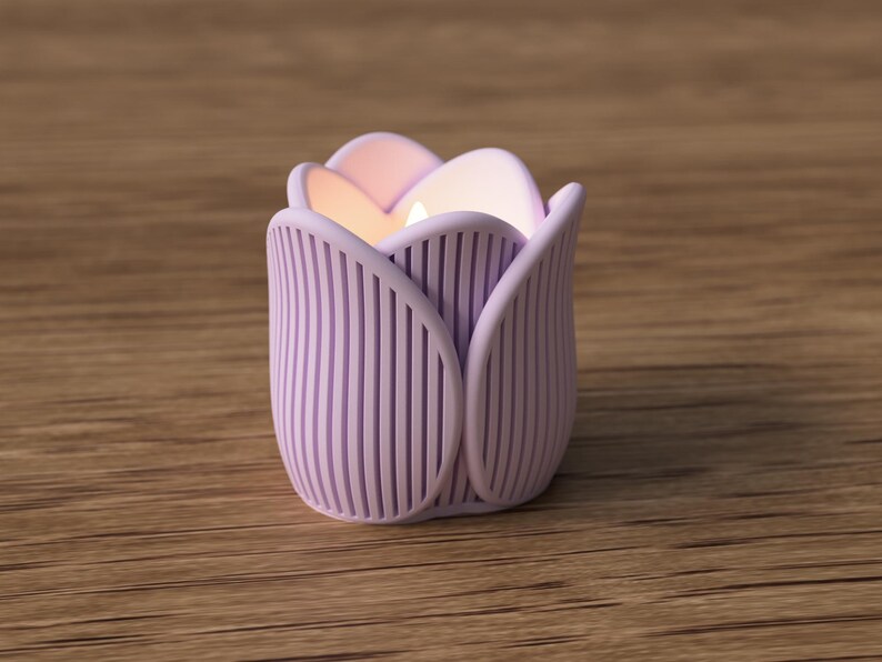 May include: A lavender tulip-shaped candle holder with vertical lines. The candle holder has a lit candle inside, emitting a warm glow. The candle holder is sitting on a wooden surface.