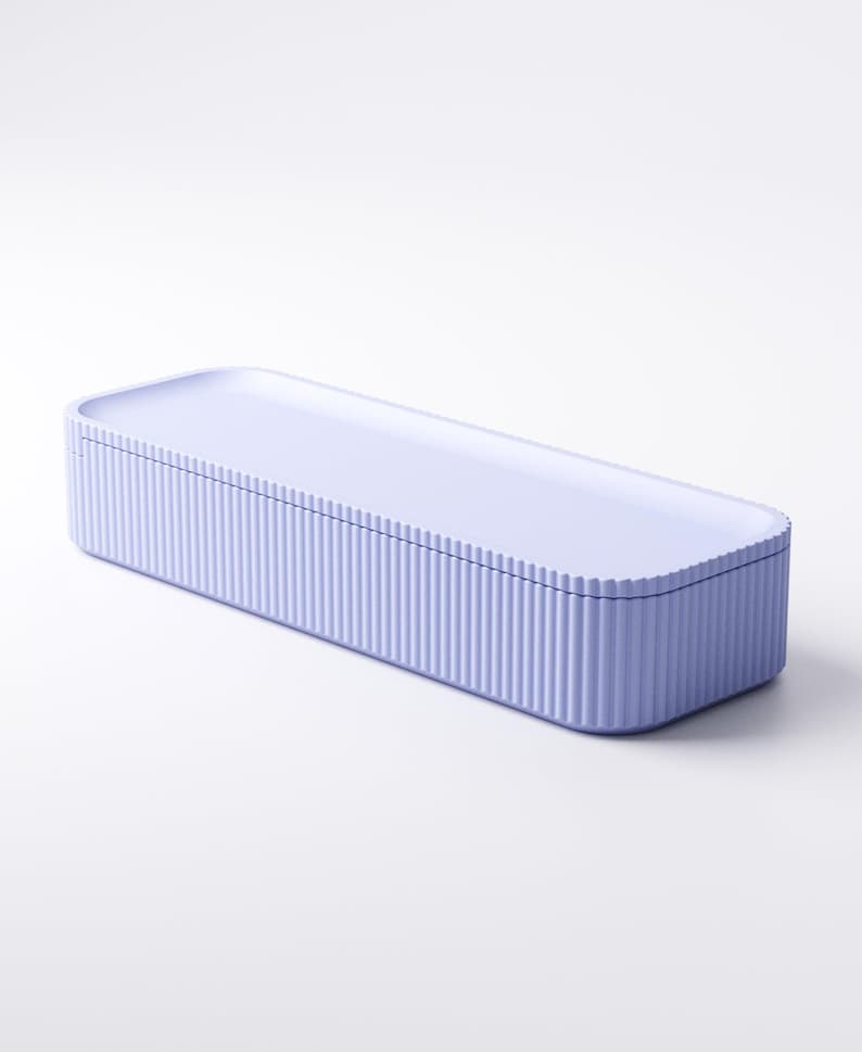 May include: A rectangular, lavender-colored storage box with a ridged exterior and a flat, matching lid. The box is designed with rounded corners and a smooth, solid top. The overall aesthetic is minimalist and modern.