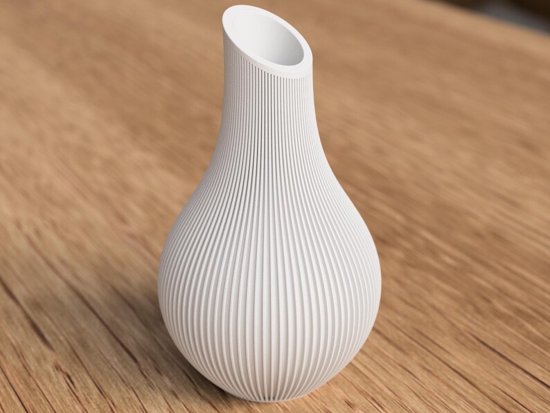 May include: A white, textured vase with a bulbous base and a flared, angled opening. The vase has vertical, ridged detailing, creating a ribbed effect. The vase is set against a wooden surface.