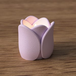 May include: A lavender-colored tulip-shaped candle holder with a textured surface. The candle holder has a soft, matte finish and is designed to resemble a blooming tulip. The interior glows with a warm, inviting light.
