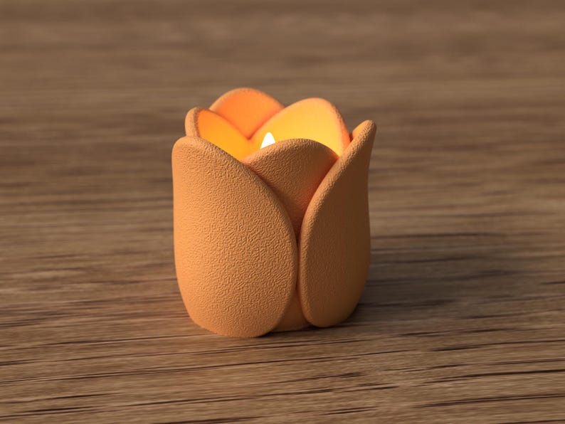 May include: A peach-colored candle holder shaped like a tulip flower. The candle holder has a textured surface and contains a lit candle, emitting a warm glow. The background is a wooden surface.