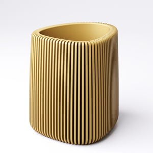 May include: A cylindrical, yellow-toned container with vertical, evenly spaced grooves. The top opening is oval-shaped. The container has a rounded base and is set against a white background. The design gives the container a textured appearance.