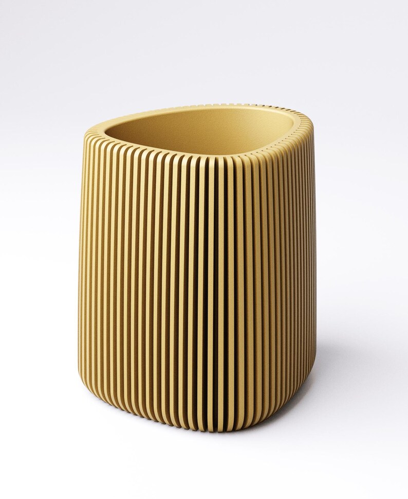 May include: A cylindrical, yellow-toned container with vertical, evenly spaced grooves. The top opening is oval-shaped. The container has a rounded base and is set against a white background. The design gives the container a textured appearance.
