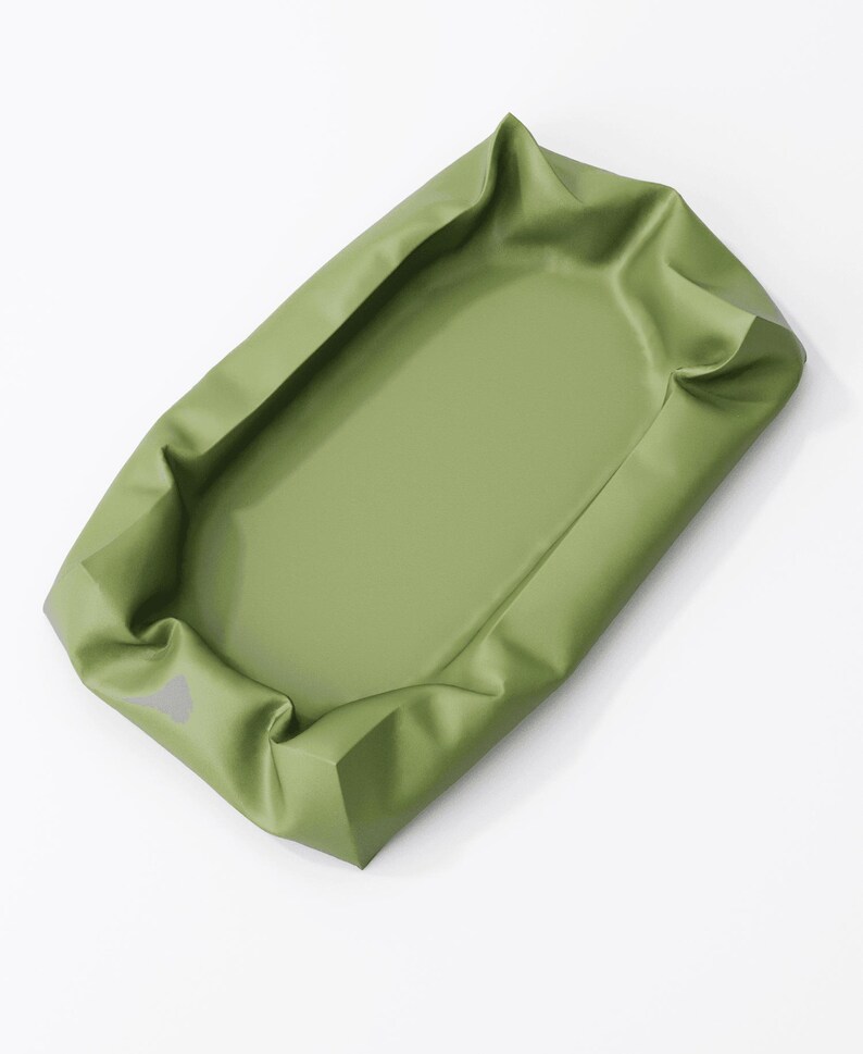 May include: An olive green rectangular tray with raised edges. The tray has a smooth, matte finish and appears to be made of a flexible material. The edges are folded over, creating a defined border.