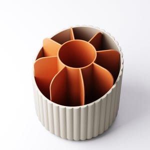 May include: A beige and orange desk organizer with a circular design. The organizer has a beige, ridged exterior and an orange interior divided into multiple compartments. The central compartment is also orange. The organizer is designed to hold pens, pencils, and other office supplies.