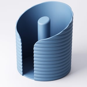 May include: A blue paper towel holder with a cylindrical center post. The holder has a curved, ridged exterior and a rounded opening. The design is modern and minimalist, with a solid blue color.