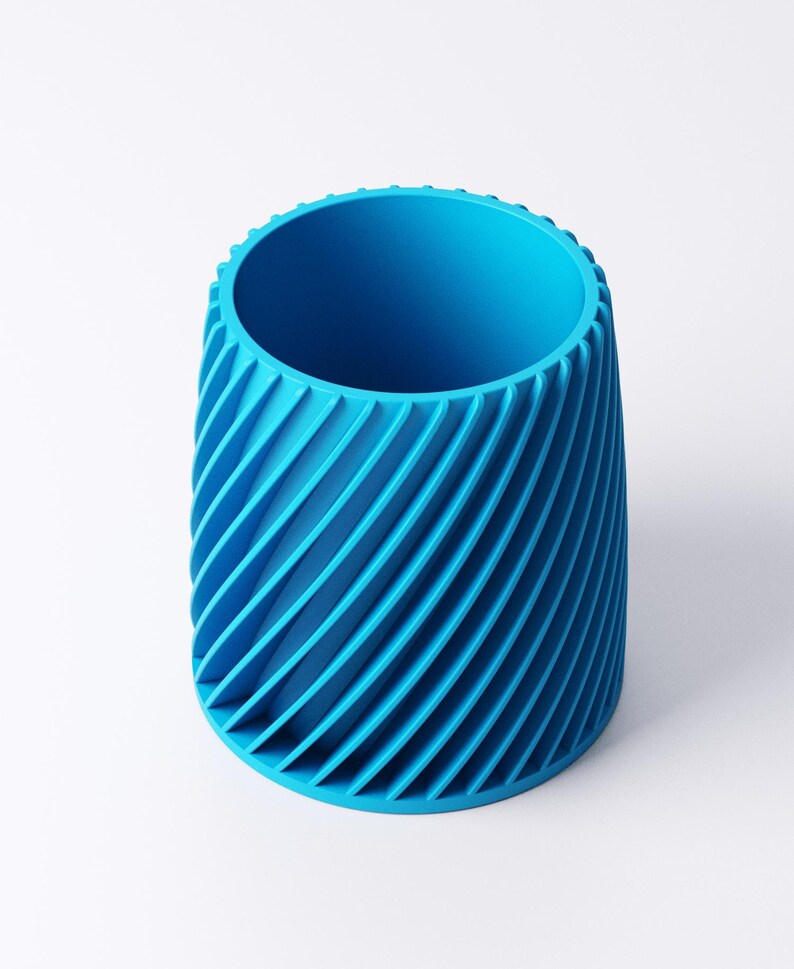 K&ouml;nnte beinhalten: Ein leuchtend blaues zylindrisches Gef&auml;&szlig; mit einem spiralf&ouml;rmigen Rippendesign. Der Beh&auml;lter hat eine breite &Ouml;ffnung oben und einen festen Boden. Das gerippte Muster erzeugt eine strukturierte Oberfl&auml;che und erh&ouml;ht die visuelle Attraktivit&auml;t.