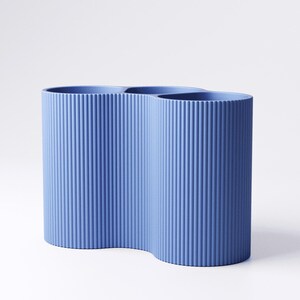 May include: A blue vase with a unique, wavy design. The vase has a textured, ribbed surface and a curved shape. The vase is made of a solid material and is suitable for home decor.