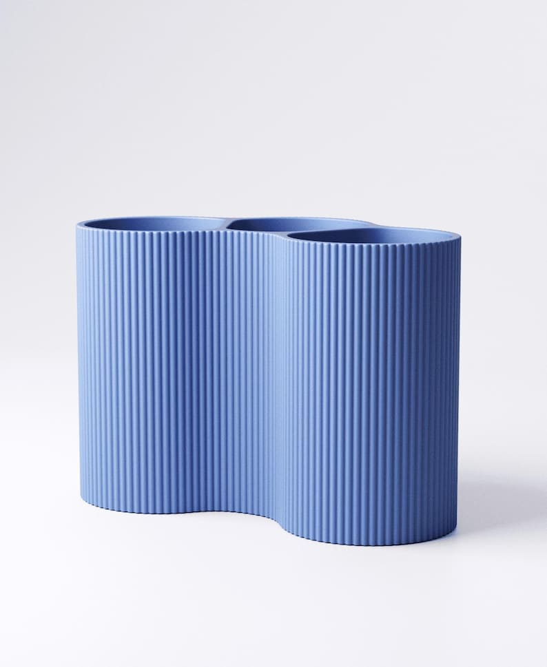 May include: A blue vase with a unique, wavy design. The vase has a textured, ribbed surface and a curved shape. The vase is made of a solid material and is suitable for home decor.