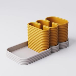 Puede incluir: Dise&ntilde;o moderno y abstracto con tres estructuras amarillas en forma de U, acanaladas, sobre una base gris, con una bandeja rectangular a juego. Los objetos tienen una est&eacute;tica minimalista y est&aacute;n sobre un fondo blanco.