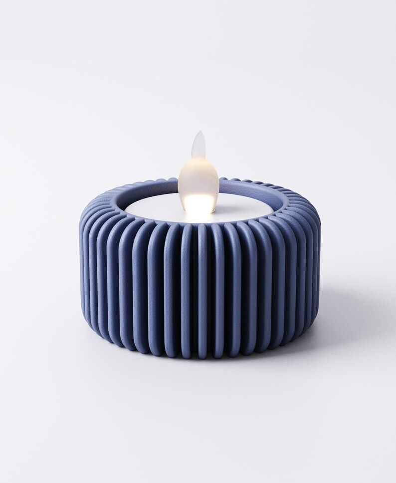 May include: A blue LED candle with a ribbed, cylindrical base. The candle has a white top and a flickering, flame-shaped light. The design is modern and minimalist, suitable for home decor.
