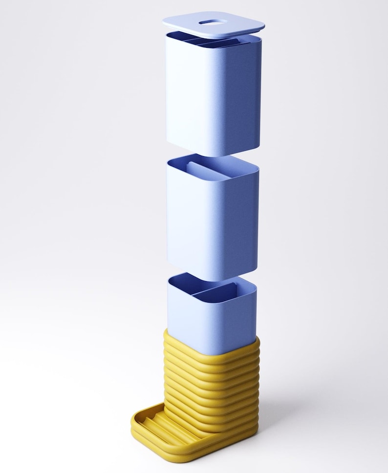 May include: A modular, three-part container in shades of blue and yellow. The top section is a light blue lid. The middle sections are light blue containers. The base is a yellow, ribbed structure with a small tray. The design is modern and minimalist.