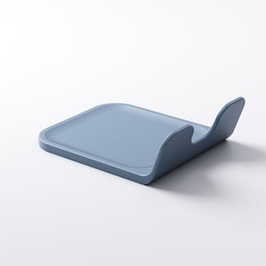 Op de afbeelding: Een lichtblauwe, rechthoekige keukengerei-houder met een gebogen handvat. De houder is gemaakt van een stevig materiaal en is ontworpen om kookgerei vast te houden. Het ontwerp is minimalistisch en modern.