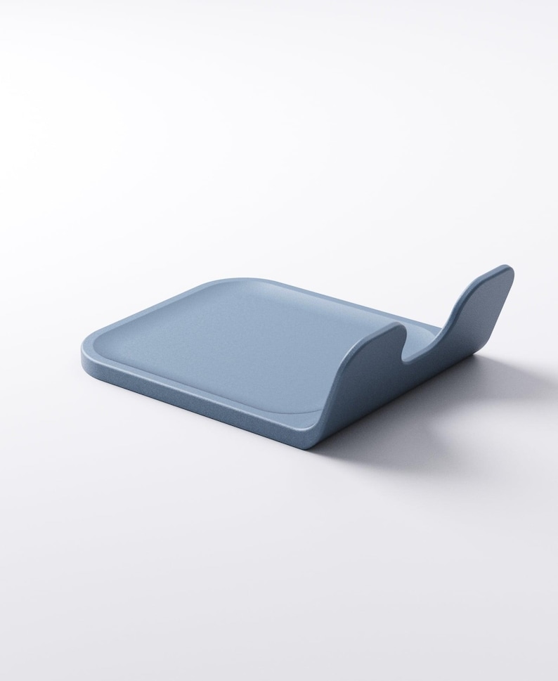 Op de afbeelding: Een lichtblauwe, rechthoekige keukengerei-houder met een gebogen handvat. De houder is gemaakt van een stevig materiaal en is ontworpen om kookgerei vast te houden. Het ontwerp is minimalistisch en modern.