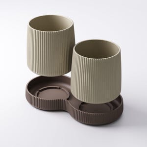 May include: Two beige ribbed ceramic tumblers sit above a brown, double-sectioned tray. The tumblers have a cylindrical shape with vertical grooves. The tray has a similar ribbed design around its edges, creating a cohesive set.