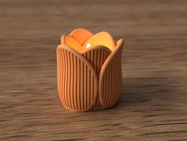 May include: A candle holder shaped like a tulip flower, with a warm orange glow emanating from within. The holder is a light orange color with vertical lines, and sits on a wooden surface.