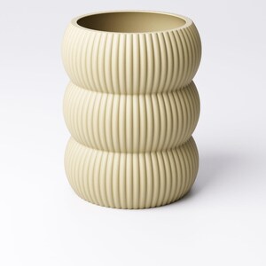May include: A light beige, ribbed ceramic vase with a stacked, rounded design. The vase has a wide opening and a textured, vertical groove pattern. The neutral color and unique shape make it a decorative home accent.