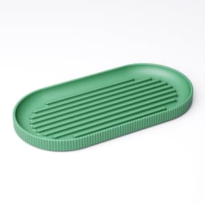 May include: A green, oval-shaped soap dish with a ribbed design. The dish has a series of parallel ridges across the center for drainage and a textured border. The soap dish is made of a solid, matte material.