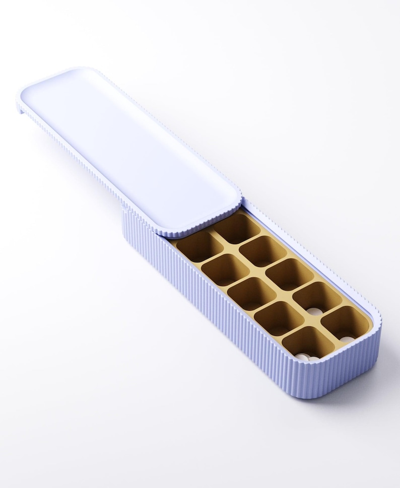 May include: A light purple rectangular ice cube tray with a matching lid. The tray has a ribbed exterior and a gold-colored interior with square compartments. The lid is open, revealing the compartments.