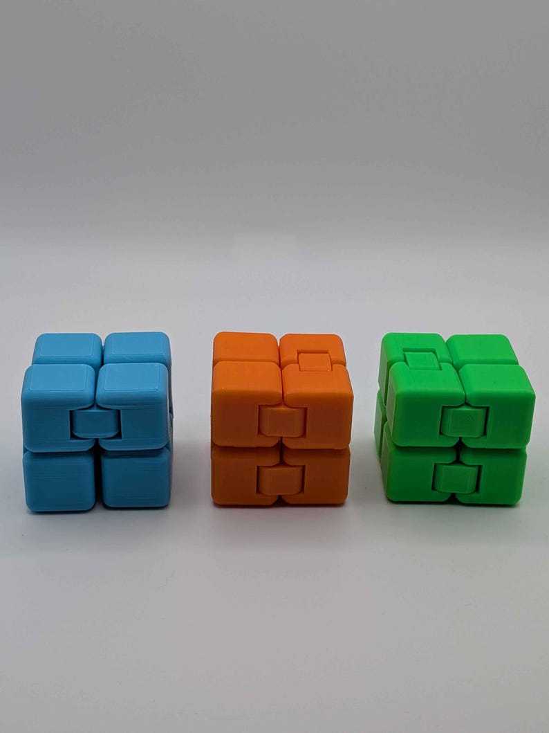 May include: Three colorful fidget cubes in blue, orange, and green. Each cube is composed of eight smaller cubes connected by hinges, allowing for flexible movement and manipulation. The cubes are arranged in a row against a white background.