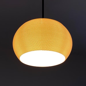 May include: A spherical pendant light fitting featuring a bright yellow exterior with a fine, textured, grid-like pattern. The bottom of the dome is open, revealing a smooth white interior surface, and the fitting is suspended by a thin black cord.