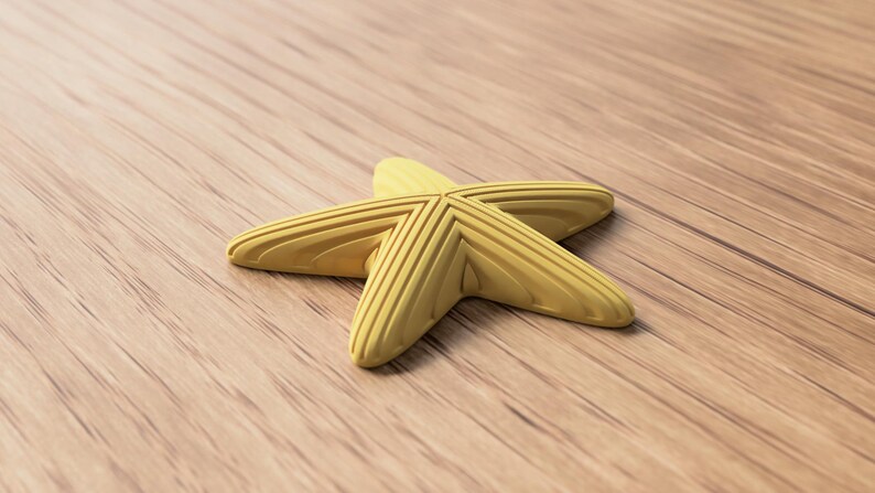 May include: A yellow starfish-shaped object with textured ridges, resting on a wooden surface. The starfish has five points and a slightly curved shape. The wooden surface has a natural wood grain pattern.