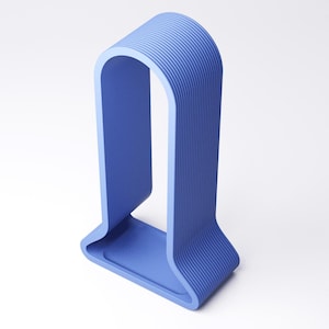 Peut inclure: Une sculpture bleue moderne et minimaliste en forme de U. Elle pr&eacute;sente une base rectangulaire et un sommet incurv&eacute;, avec des rainures verticales sur les bords ext&eacute;rieurs. La couleur est un bleu moyen uni.