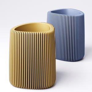 May include: Two cylindrical containers, one yellow and one blue, with vertical grooves. The yellow container has a rounded top and a smooth interior. The blue container is behind the yellow one and has a similar design.