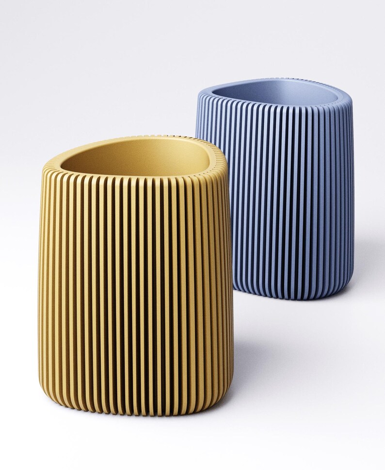 May include: Two cylindrical containers, one yellow and one blue, with vertical grooves. The yellow container has a rounded top and a smooth interior. The blue container is behind the yellow one and has a similar design.