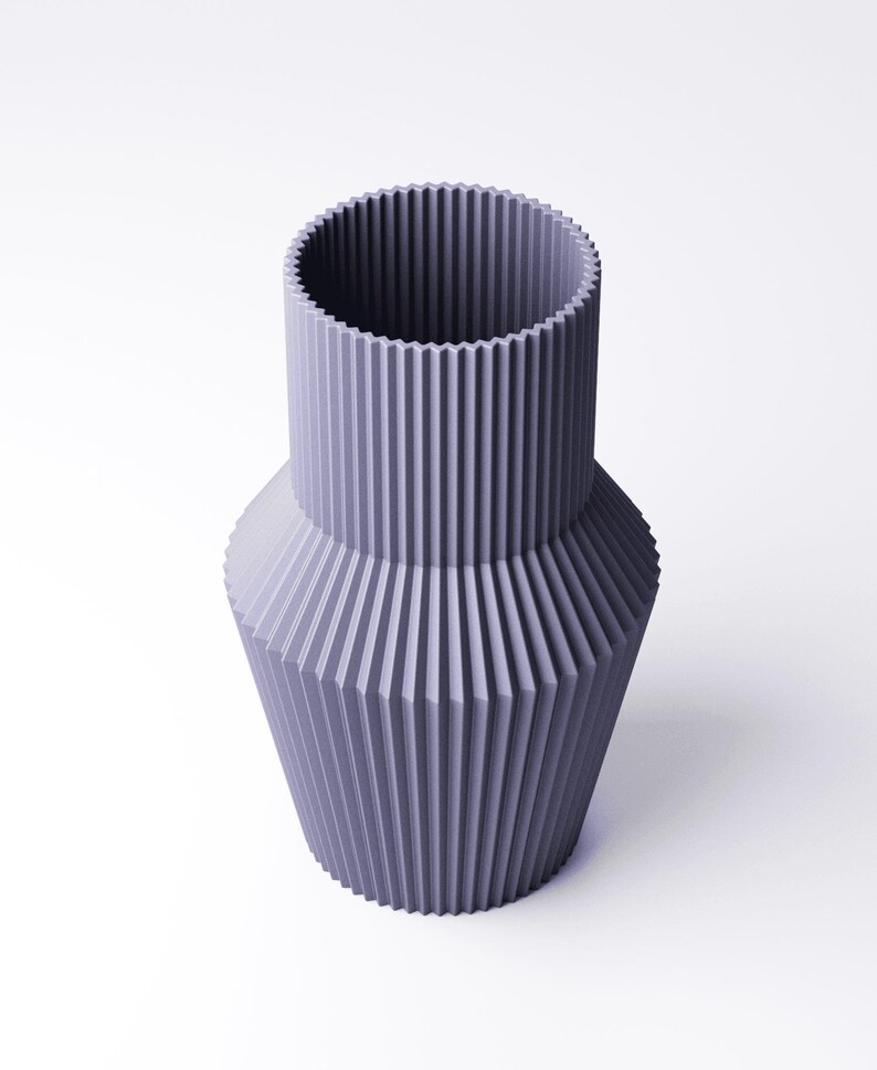 Pu&ograve; includere: Un vaso color lavanda dal design geometrico. Il vaso ha un collo cilindrico e un corpo pi&ugrave; ampio e sfaccettato. Le creste verticali corrono lungo l'intera superficie, creando un aspetto strutturato. Il vaso &egrave; realizzato in un materiale solido e poggia su uno sfondo bianco.