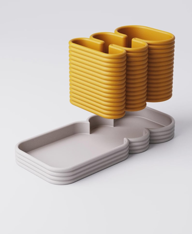 Puede incluir: Escultura abstracta moderna con base gris claro y bordes curvos apilados. Tres formas verticales amarillas en forma de U se elevan sobre la base. Dise&ntilde;o minimalista y contempor&aacute;neo.