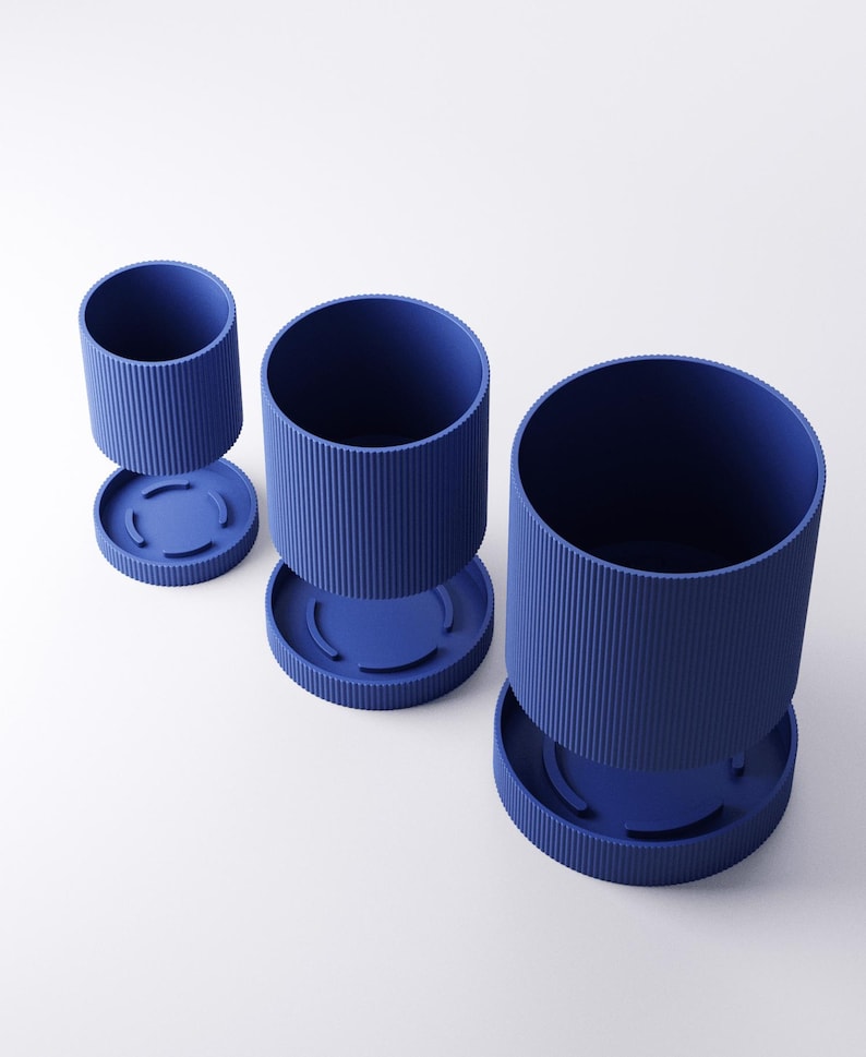 May include: Three blue cylindrical planters with a ribbed texture and matching circular bases are displayed against a white background. The planters are of varying sizes, with one detached from its base, showcasing a modern, minimalist design.
