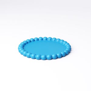 May include: A round, light blue tray with a beaded edge. The tray has a smooth, flat surface and a border of evenly spaced, rounded beads. The tray is set against a plain white background.