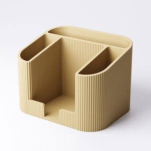 May include: A beige desk organizer with a ribbed texture. The organizer has three compartments: two angled slots and a central open area. The design is modern and minimalist, suitable for office or home use.