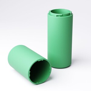 May include: Two cylindrical containers in a light mint green color, featuring a vertical ribbed texture along the exterior. One container stands upright while the other lies on its side, revealing a hollow interior and notched rim edges.