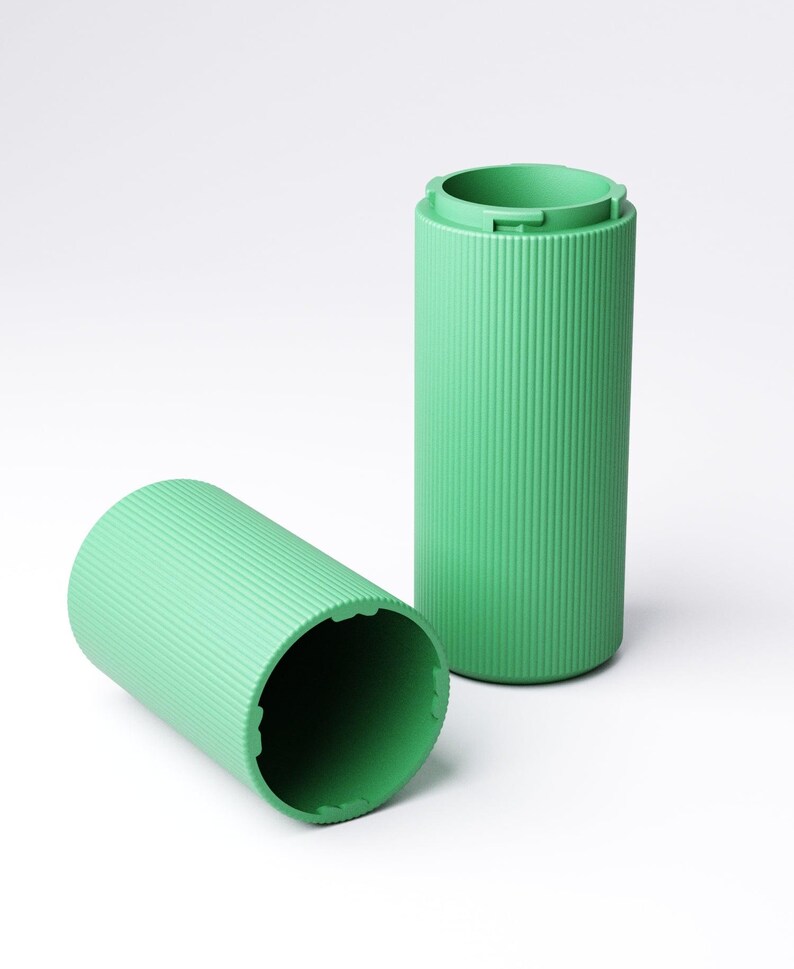 May include: Two cylindrical containers in a light mint green color, featuring a vertical ribbed texture along the exterior. One container stands upright while the other lies on its side, revealing a hollow interior and notched rim edges.