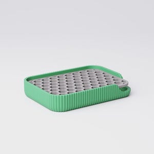 May include: A rectangular ice cube tray with a green ribbed border and a gray interior with multiple hexagonal molds. The tray has a small handle on one side. The design is modern and minimalist.